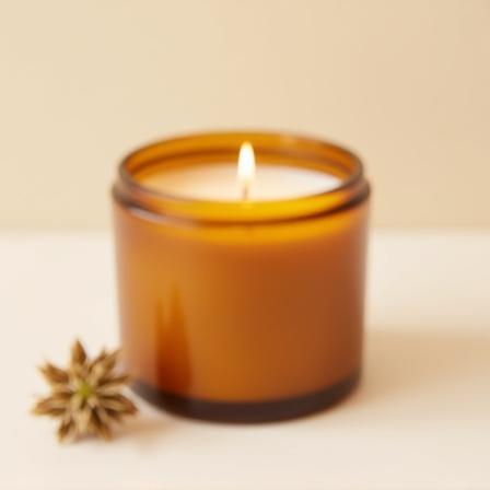 Candela artigianale in un vasetto di vetro ambrato.